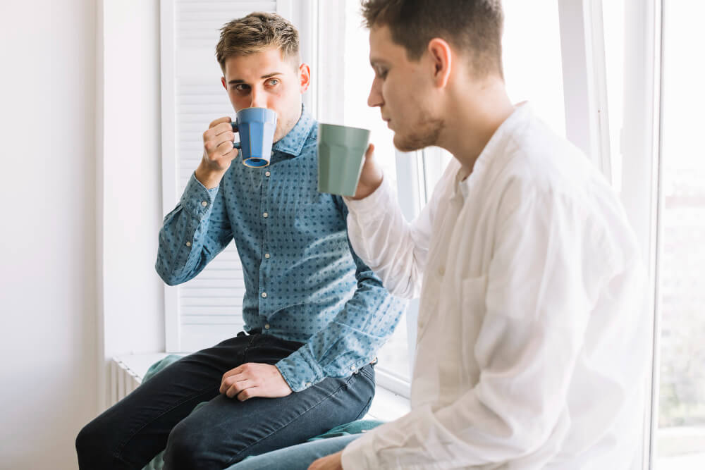 young man drinking coffee near window
